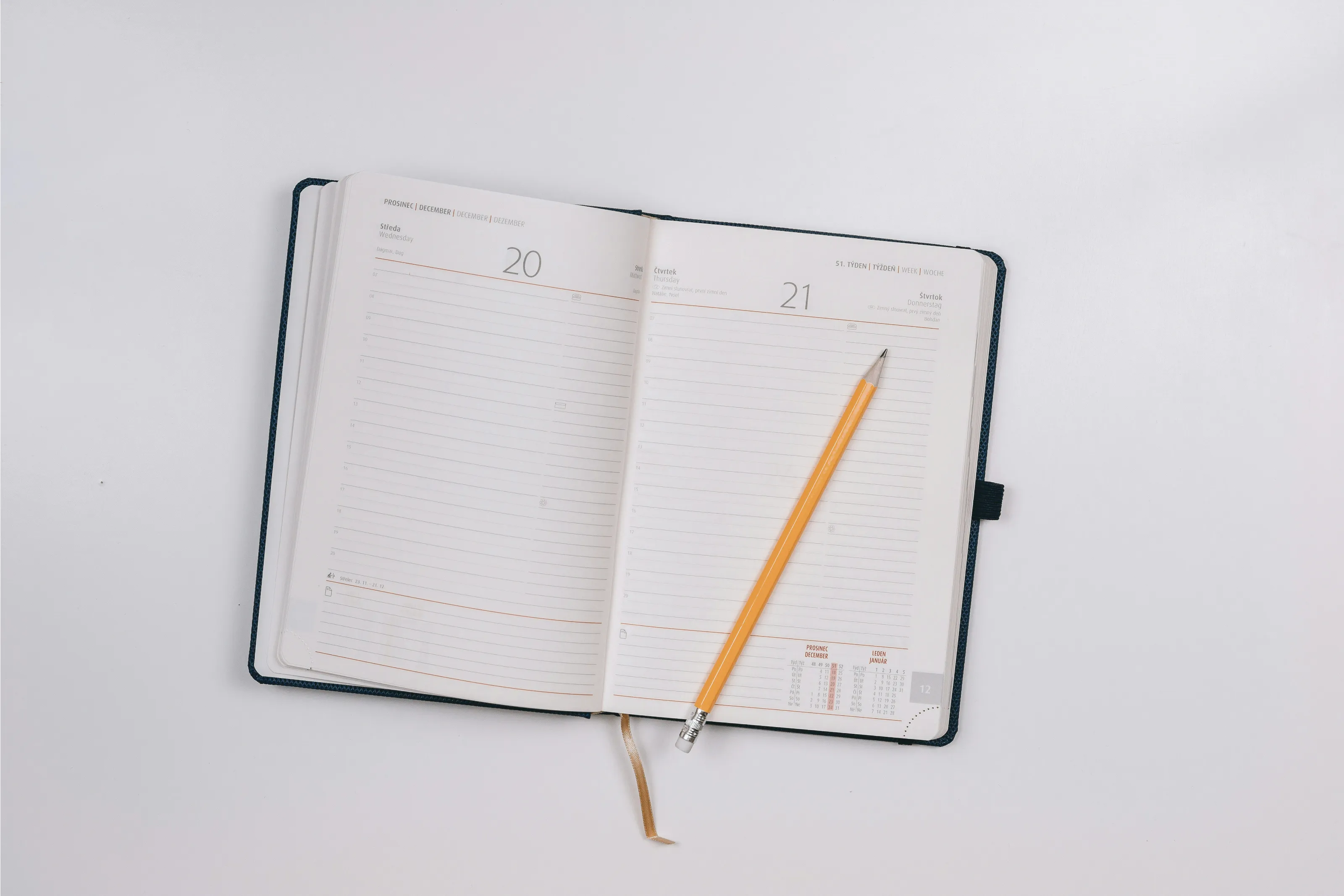 An open paper planner with a yellow pencil for recording the next update